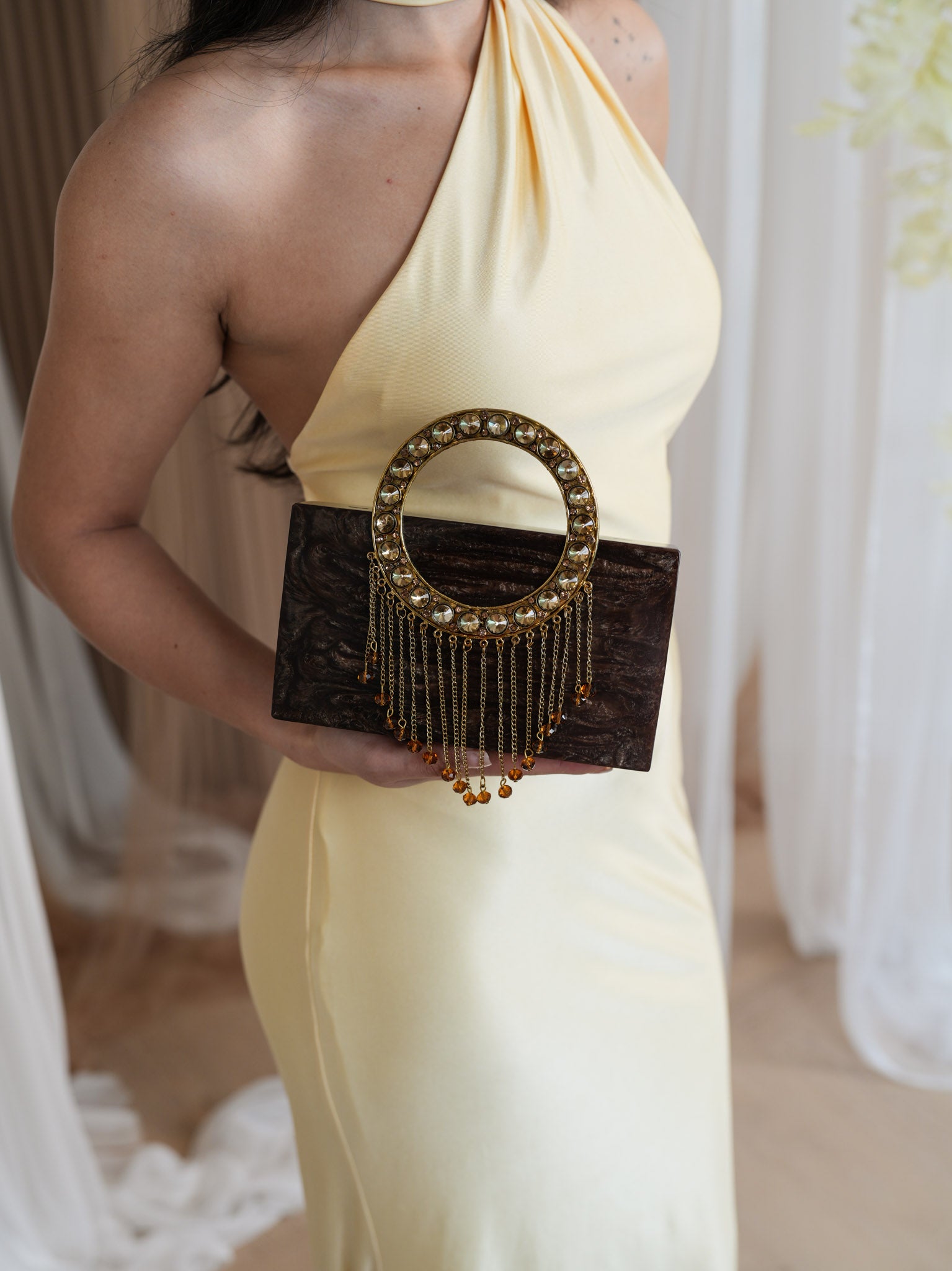 Woman in a holding a black clutch with gold accents.